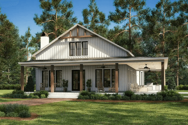 Charming barndominium with a large porch surrounded by trees.